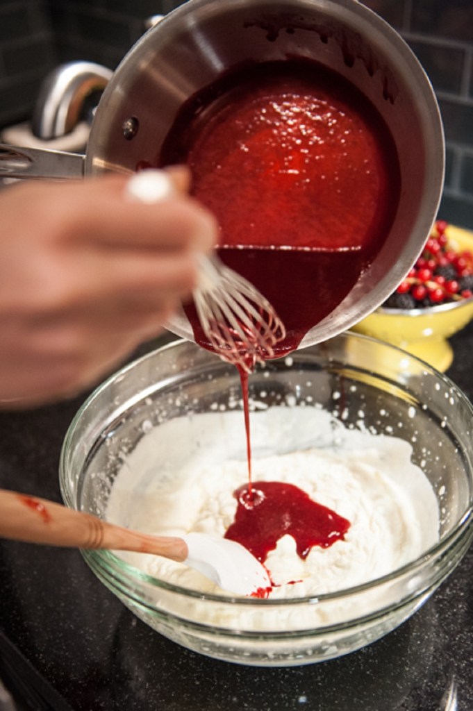 Folding in raspberry puree into the whipped cream. 